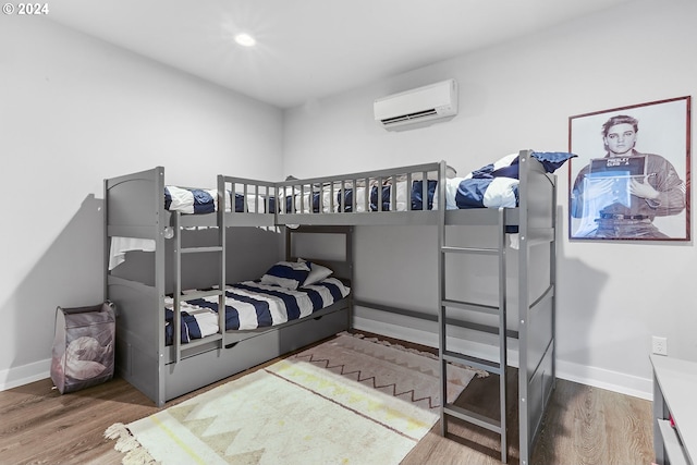 bedroom with hardwood / wood-style flooring and an AC wall unit