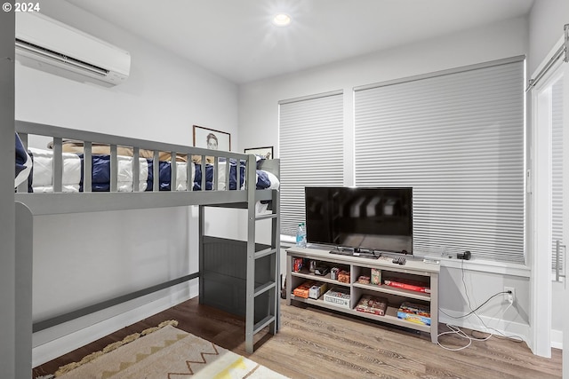 bedroom featuring a wall mounted AC and hardwood / wood-style floors