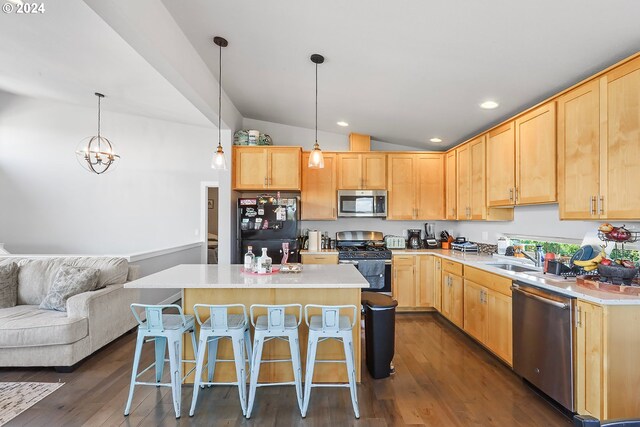 kitchen featuring stainless steel appliances, light brown cabinetry, pendant lighting, dark hardwood / wood-style floors, and vaulted ceiling