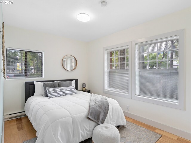 bedroom with baseboard heating and light hardwood / wood-style floors