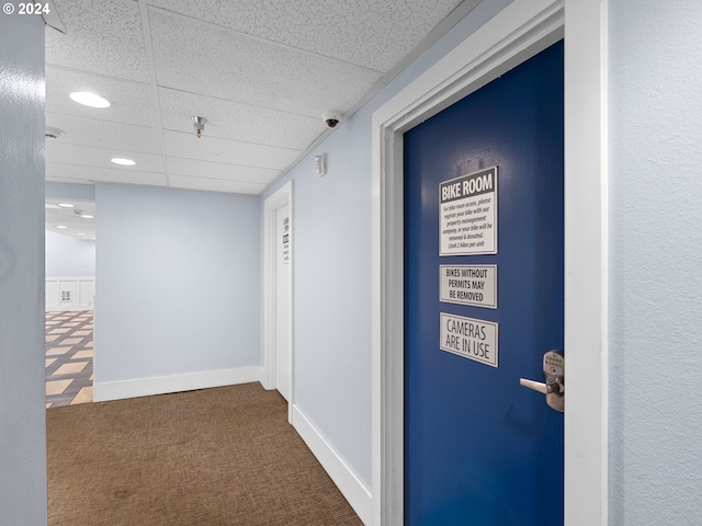 hall with carpet flooring and a drop ceiling