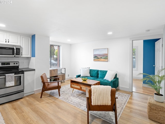 living room with recessed lighting, light wood-style flooring, and baseboards