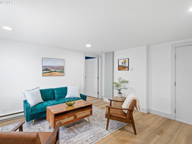 living room with a baseboard heating unit and light hardwood / wood-style floors