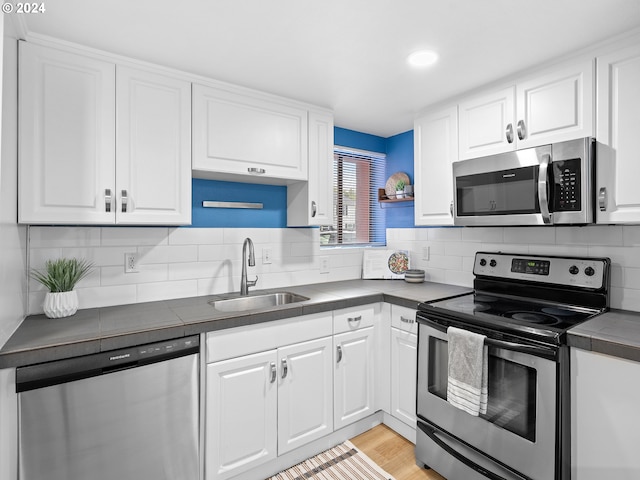 kitchen featuring stainless steel appliances, white cabinetry, a sink, and tasteful backsplash