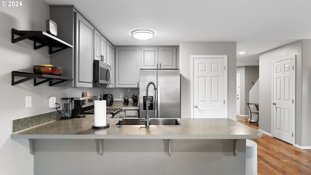 kitchen featuring kitchen peninsula, appliances with stainless steel finishes, hardwood / wood-style flooring, and a kitchen breakfast bar