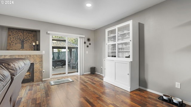 doorway to outside with dark wood-type flooring and a tiled fireplace