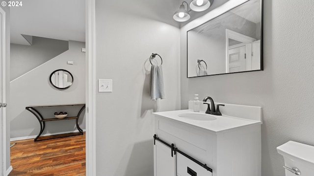 bathroom with hardwood / wood-style flooring, vanity, and toilet