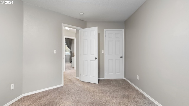 unfurnished bedroom with a textured ceiling and light carpet