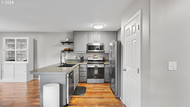 kitchen featuring light hardwood / wood-style floors, sink, kitchen peninsula, and stainless steel appliances