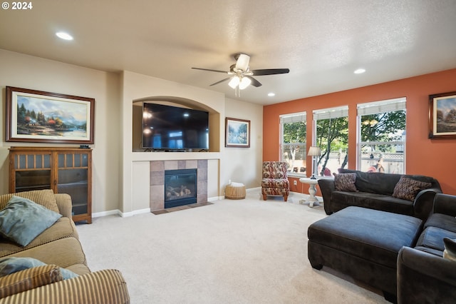 carpeted living room with a textured ceiling, a tile fireplace, and ceiling fan