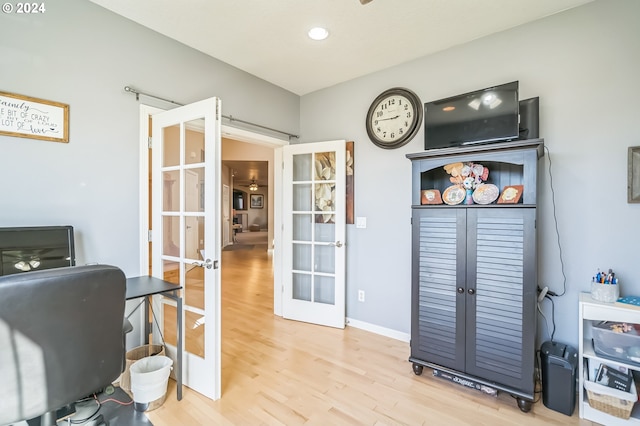 home office with light wood-type flooring and french doors