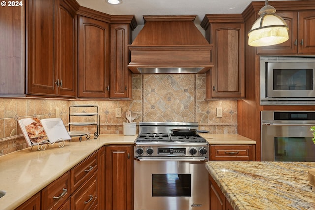 kitchen featuring custom exhaust hood, light stone counters, appliances with stainless steel finishes, pendant lighting, and backsplash