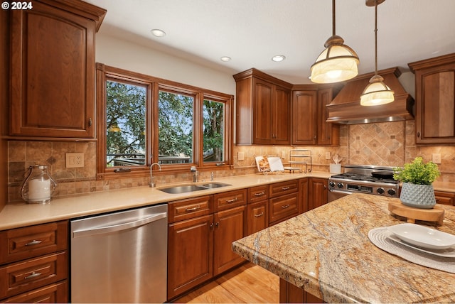 kitchen featuring sink, premium range hood, stove, hanging light fixtures, and stainless steel dishwasher