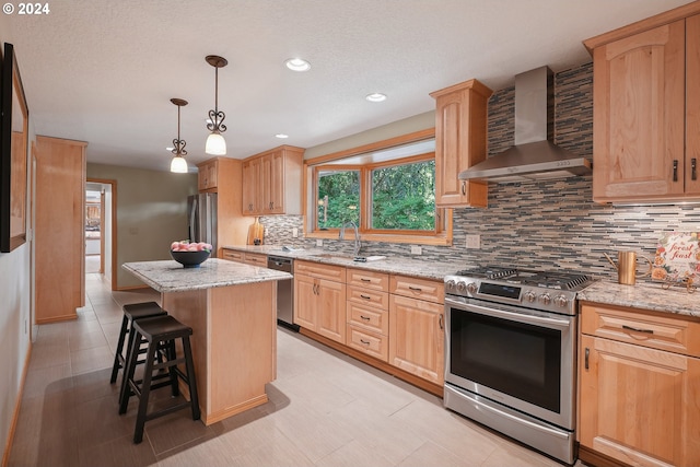 kitchen featuring a kitchen island, appliances with stainless steel finishes, backsplash, light stone countertops, and wall chimney exhaust hood