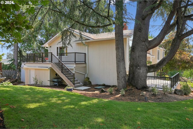 back of property with a lawn and a deck