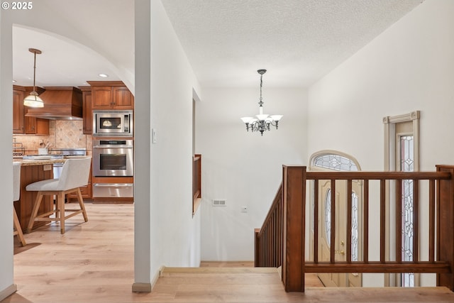 4243 Spring Rock Cir, West Linn, OR 97068 - staircase with wood finished floors, a chandelier, arched walkways, and recessed lighting