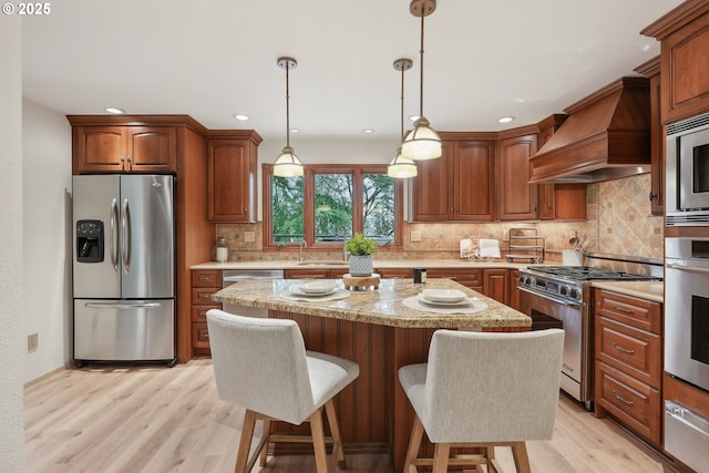 4243 Spring Rock Cir, West Linn, OR 97068 - kitchen with stainless steel appliances, premium range hood, a warming drawer, light wood-type flooring, and a kitchen island