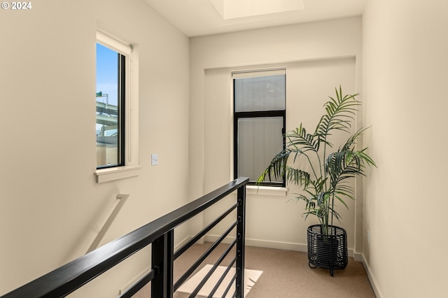 hall with carpet floors, baseboards, and an upstairs landing