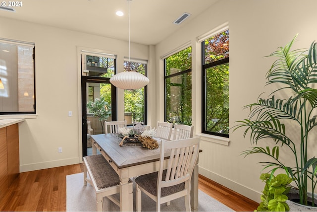 dining room featuring plenty of natural light, wood finished floors, visible vents, and baseboards