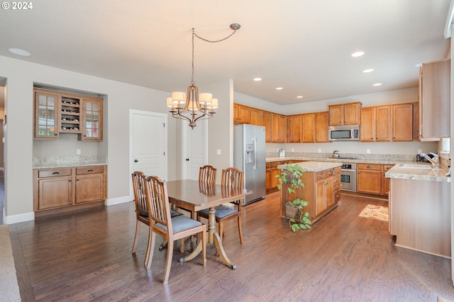 kitchen featuring a kitchen island, decorative light fixtures, dark wood-type flooring, stainless steel appliances, and a notable chandelier