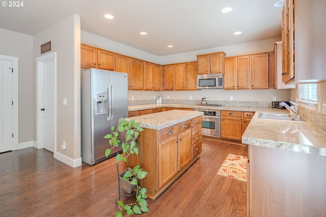 kitchen with sink, hardwood / wood-style floors, stainless steel appliances, and a kitchen island