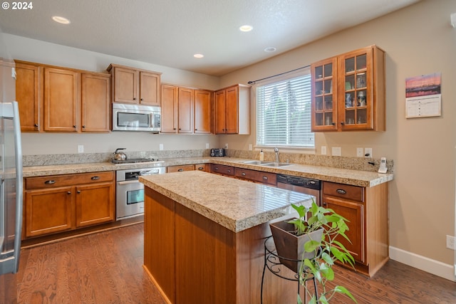 kitchen featuring a center island, dark wood-type flooring, stainless steel appliances, sink, and a breakfast bar area