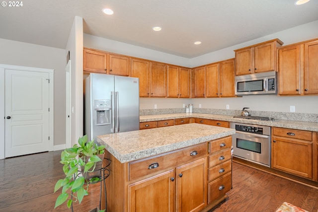 kitchen featuring dark hardwood / wood-style flooring, light stone countertops, a center island, and stainless steel appliances