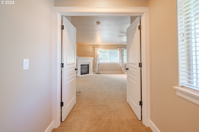 corridor featuring light colored carpet and a textured ceiling