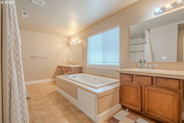 bathroom with a textured ceiling, a tub to relax in, and vanity