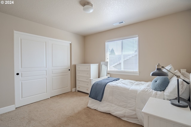 carpeted bedroom featuring a textured ceiling and a closet