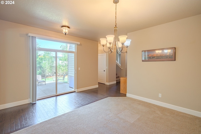 spare room with dark hardwood / wood-style flooring, an inviting chandelier, and a textured ceiling