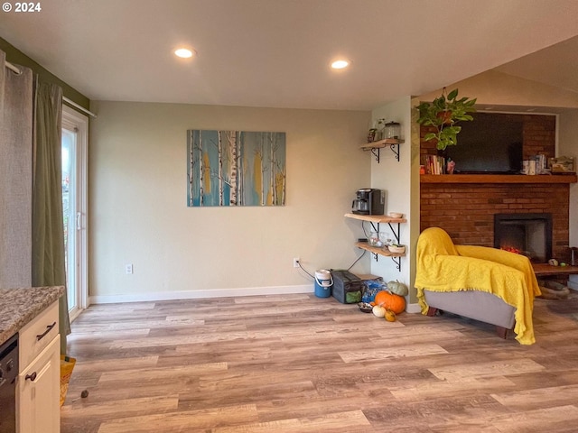 living area with a brick fireplace and light hardwood / wood-style flooring