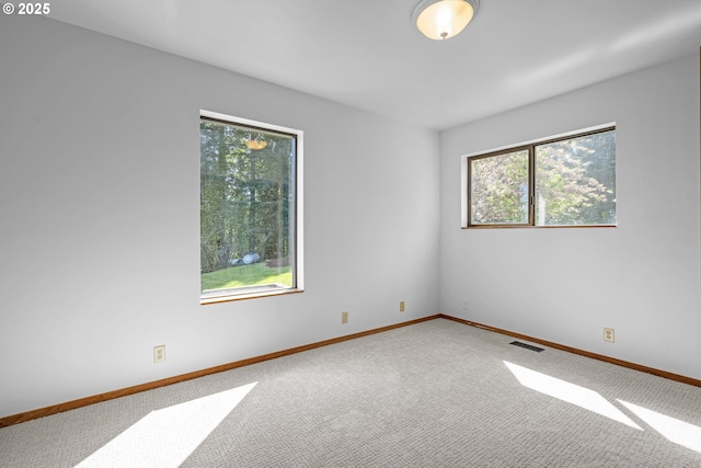 carpeted empty room featuring baseboards and visible vents
