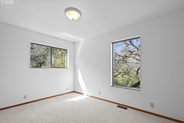 carpeted empty room featuring baseboards and visible vents