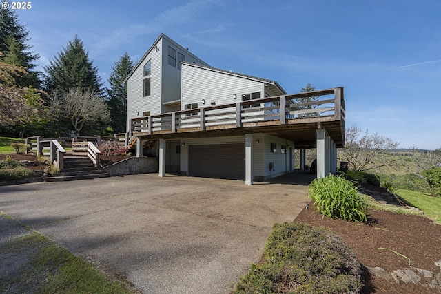 view of property exterior with an attached garage, a wooden deck, driveway, and stairway