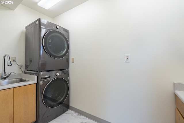 clothes washing area featuring a sink, cabinet space, stacked washing maching and dryer, and marble finish floor