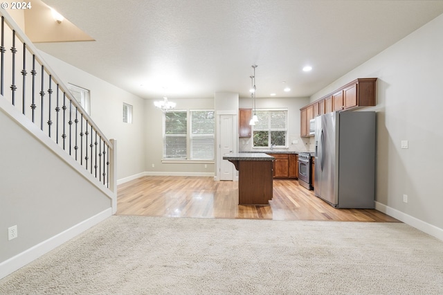 kitchen with a center island, a kitchen breakfast bar, appliances with stainless steel finishes, decorative light fixtures, and light hardwood / wood-style floors