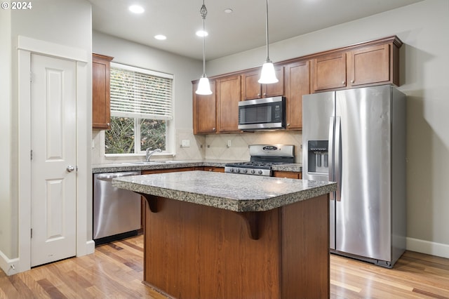 kitchen featuring appliances with stainless steel finishes, light wood-type flooring, tasteful backsplash, and a kitchen island