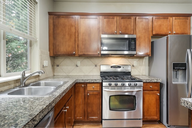 kitchen featuring tasteful backsplash, sink, light hardwood / wood-style flooring, and appliances with stainless steel finishes