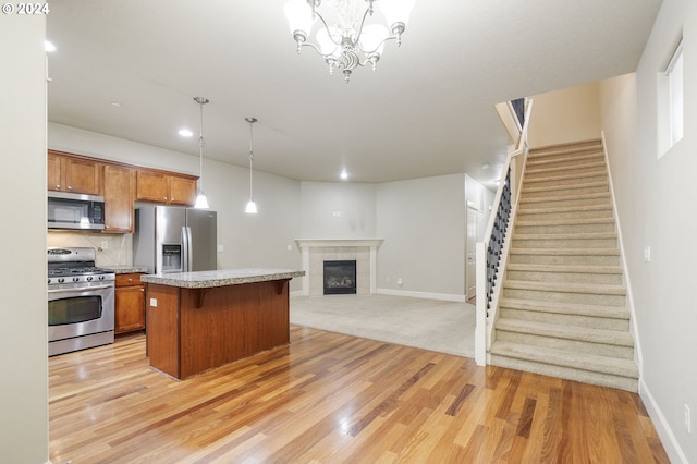 kitchen featuring a kitchen bar, stainless steel appliances, a kitchen island, hanging light fixtures, and a tiled fireplace