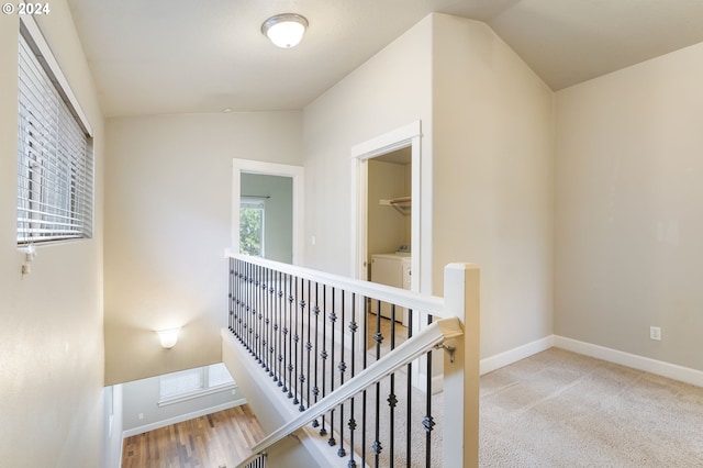 hall featuring light colored carpet, lofted ceiling, and separate washer and dryer