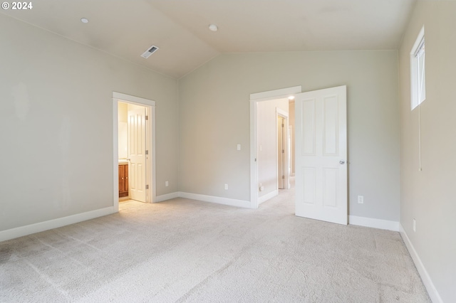 unfurnished bedroom featuring connected bathroom, light colored carpet, and lofted ceiling