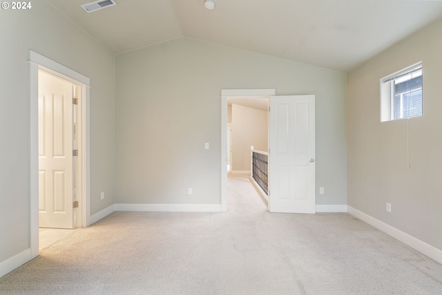 spare room with light carpet and vaulted ceiling