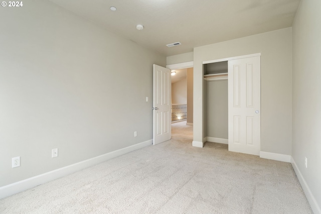 unfurnished bedroom featuring light colored carpet and a closet