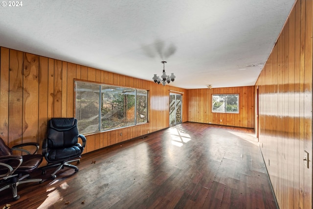 interior space featuring hardwood / wood-style floors, a textured ceiling, a notable chandelier, and wood walls