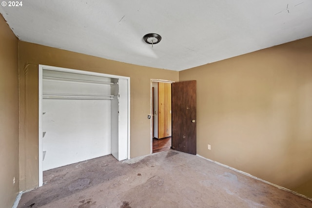 unfurnished bedroom featuring concrete floors and a closet