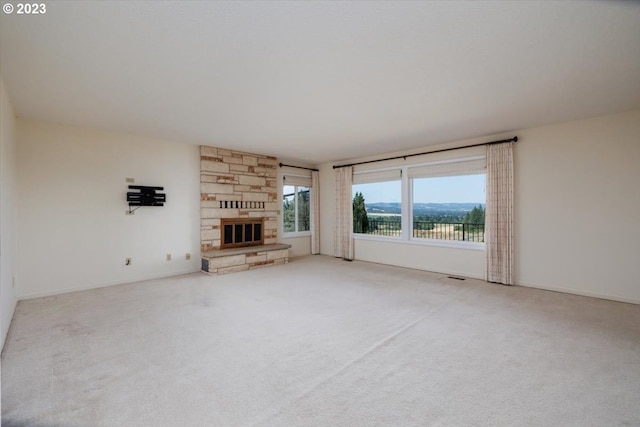 unfurnished living room with light carpet and a stone fireplace