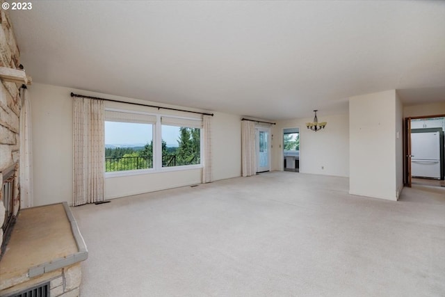 unfurnished living room with a notable chandelier, a fireplace, and light colored carpet