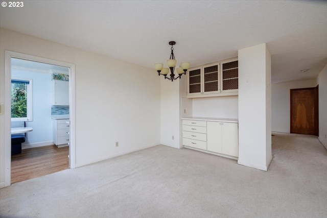 unfurnished dining area featuring an inviting chandelier and light colored carpet