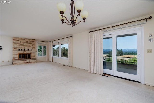 unfurnished living room featuring a fireplace, a chandelier, and carpet floors